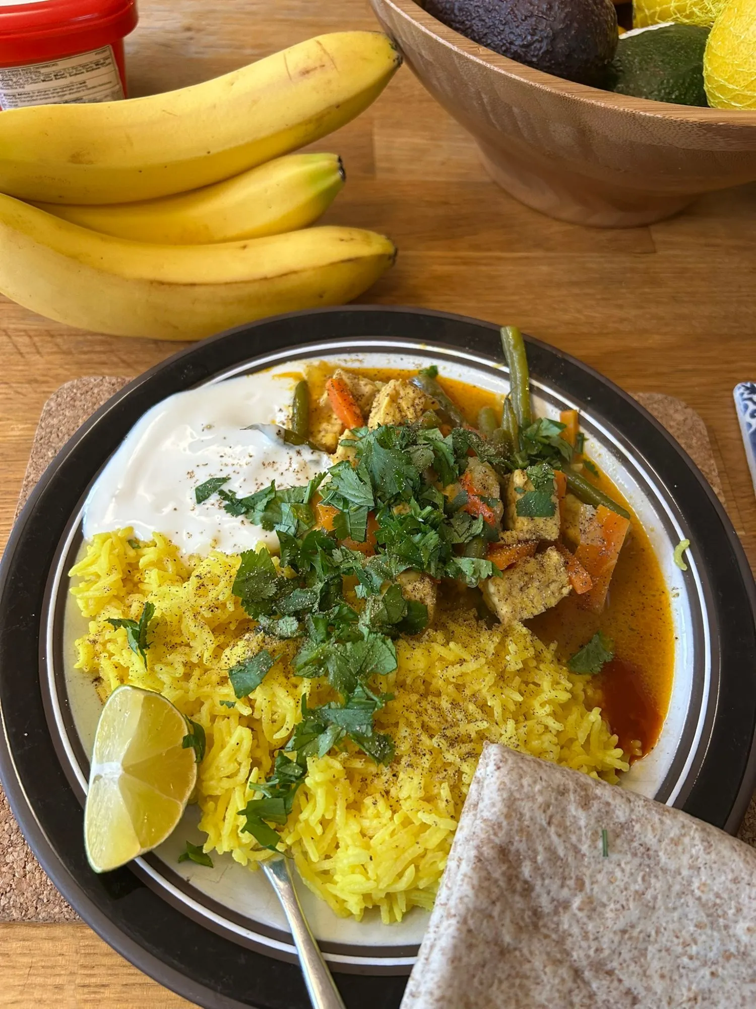 Indonesian curry with tempeh, green beans and carrots, served with yellow rice, yogurt, lime and roti